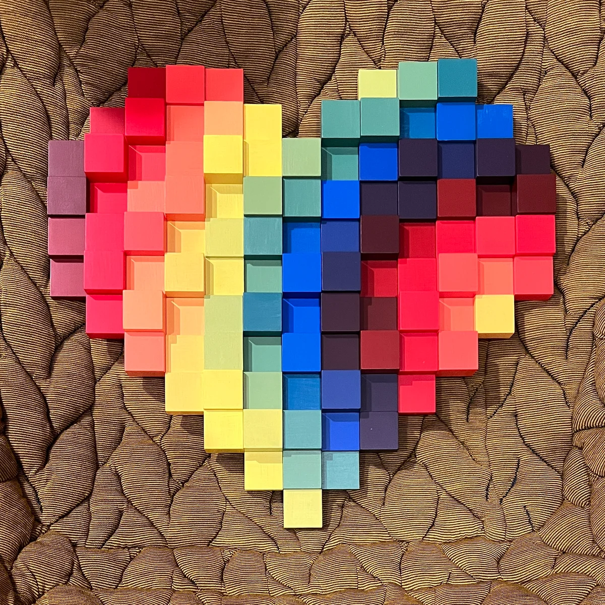 A large assembled Heart + Craft on quilted fabric, with painted blocks in pink, yellow, green, turquoise, blue, and purple.