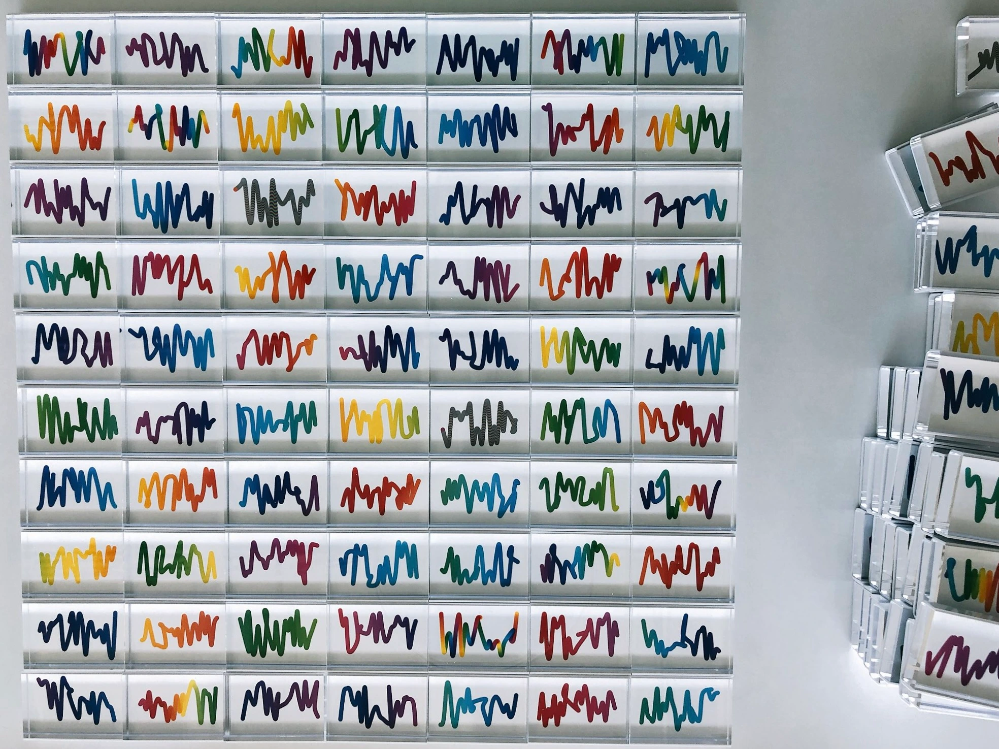 Dozens of early Squiggle prints arranged in a grid, with more frames stacked along the right side.