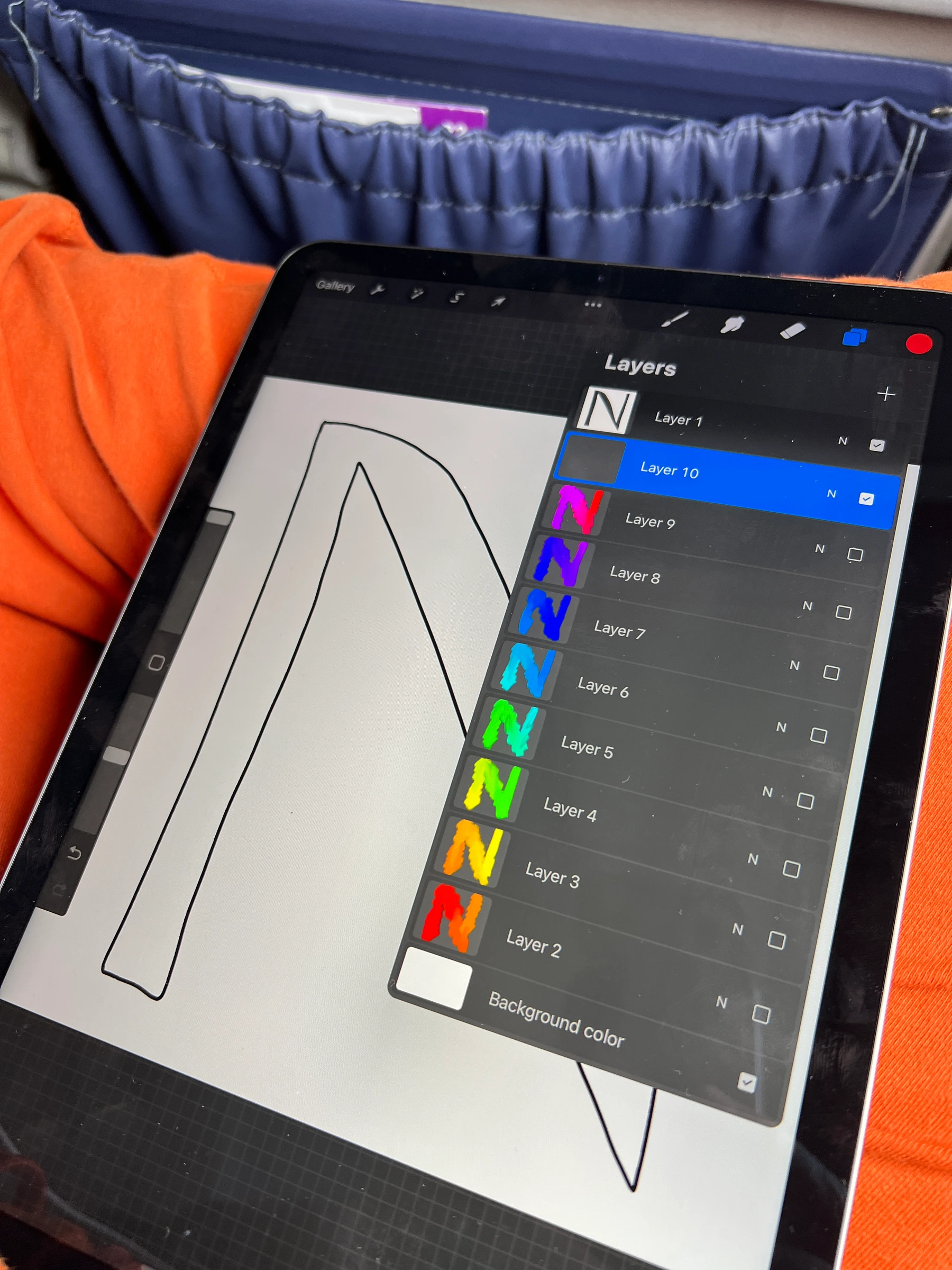 A tablet displaying the outline of an N beside a layers panel with versions in different pairs of colors.